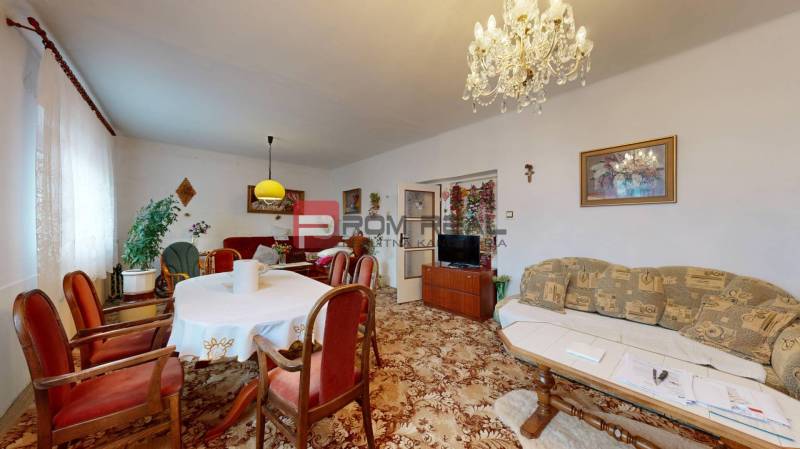 Wohnzimmer in einem Einfamilienhaus mit Möbeln, Teppich, Kronleuchter, Vorhängen und Bildern.