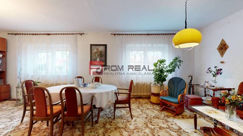 Wohnzimmer in einem Einfamilienhaus mit Tisch, Stühlen, Dekorationen und einer gelben Deckenleuchte.