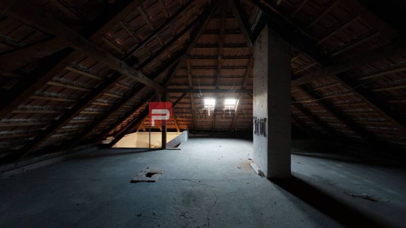 Dachboden in einem Einfamilienhaus mit Holzbalken und Dachfenstern.