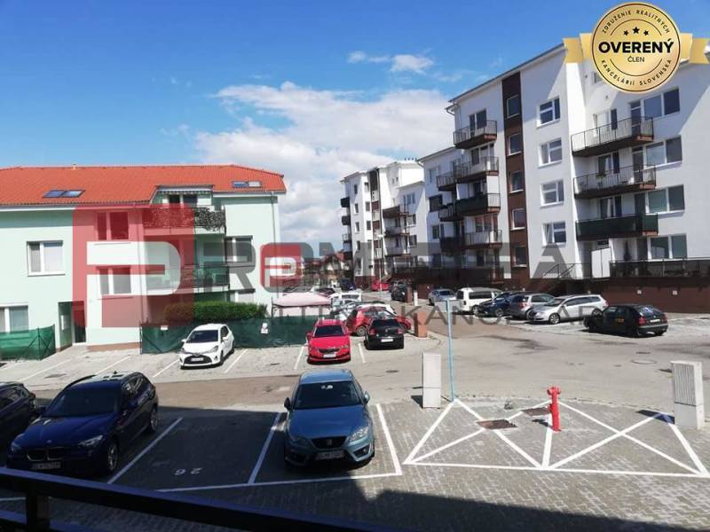 Parkplatz in der Slavomírova-Straße mit Autos vor Gebäuden in einer städtischen Umgebung.