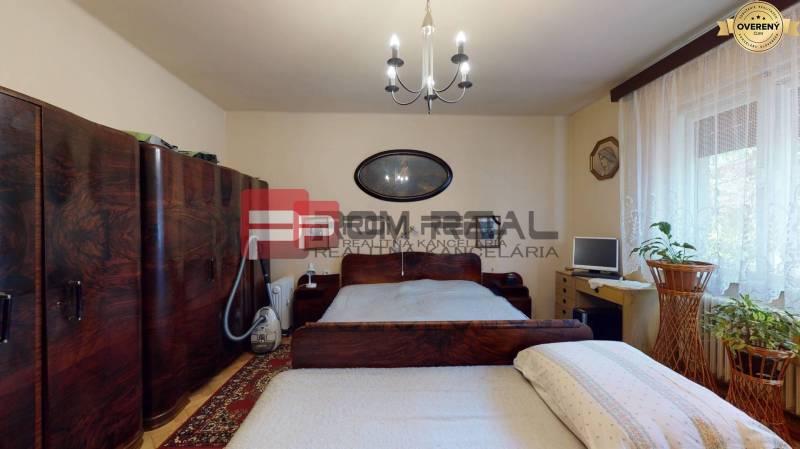 Ein Schlafzimmer in einem Einfamilienhaus mit Holzmöbeln, einem Fernseher und Vorhängen am Fenster.