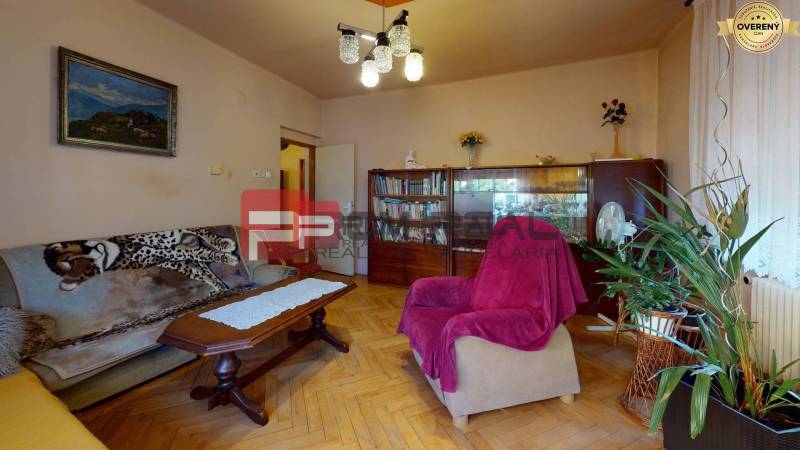 Wohnzimmer in einem Einfamilienhaus mit Sofa, Sessel, Bild und Pflanzen.