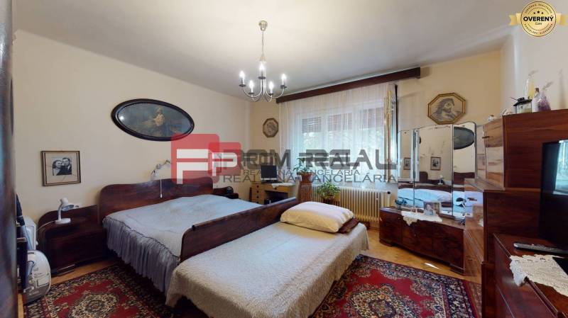 Schlafzimmer im Einfamilienhaus mit Holzmöbeln, Teppich und Bildern.