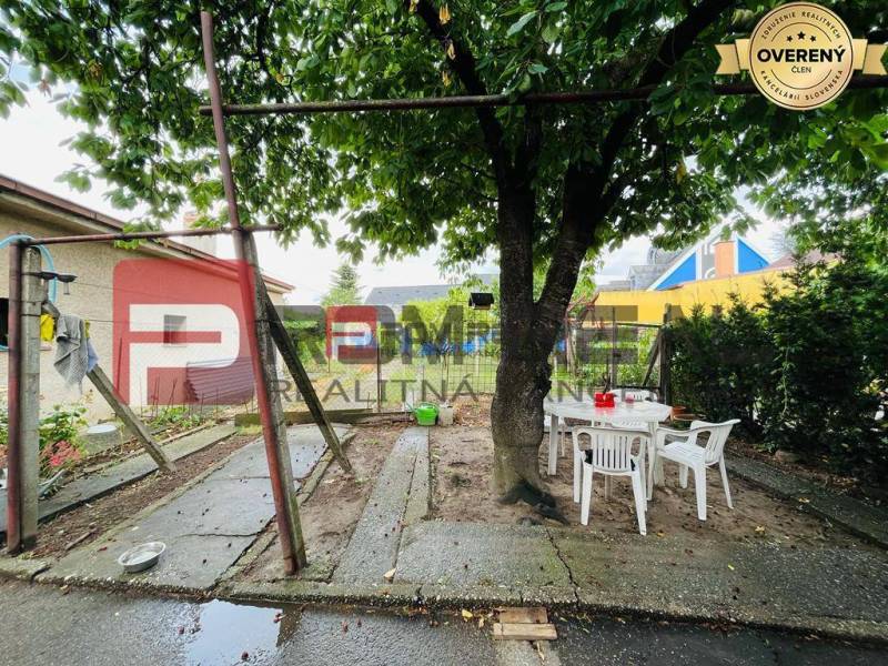 Ein Einfamilienhaus in der Nerudova-Straße in Pezinok, ein Garten mit einem Baum und Plastikmöbeln.