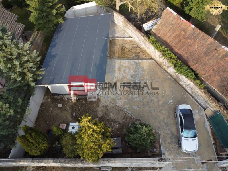 Luftaufnahme eines Familienhausgartens in Pezinok mit geparktem Auto und Garage.