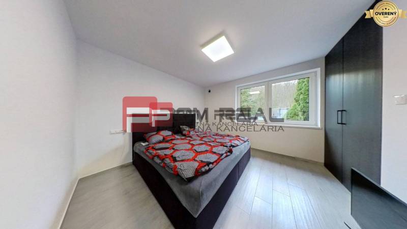 Ein Schlafzimmer in einem Einfamilienhaus mit einem Doppelbett, dunklen Möbeln und großen Fenstern.