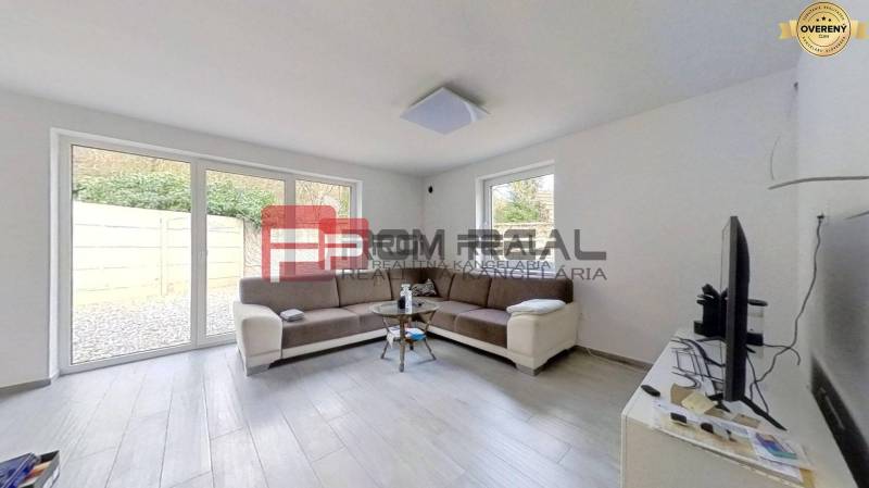 Wohnzimmer in einem Einfamilienhaus mit Sofa, Fenstern und Fernseher.