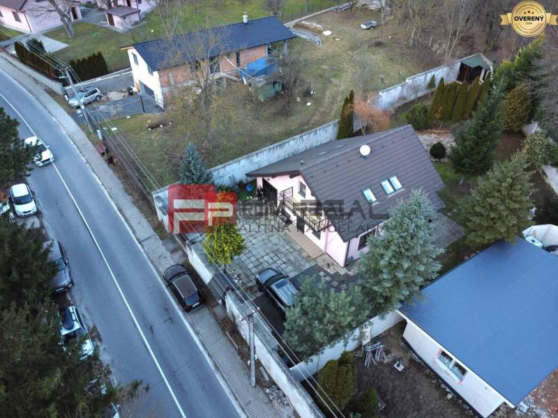 Ein Einfamilienhaus in Píla an der Straße, mit zwei Autos und einem gepflegten Garten.
