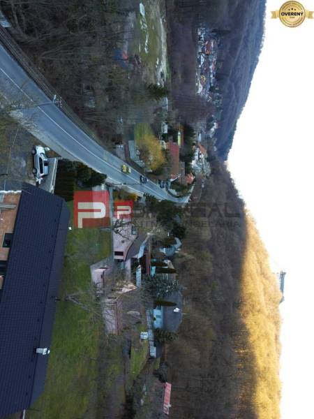 Einfamilienhäuser im Dorf Píla, gesäumt von Straße und Wald.