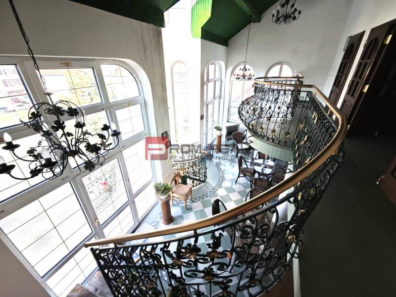 Das Innere zeigt eine elegante Treppe und einen Balkon in der Ľ. Podjavorinská-Straße, übergroße Fenster betonen das historische Gebäude.