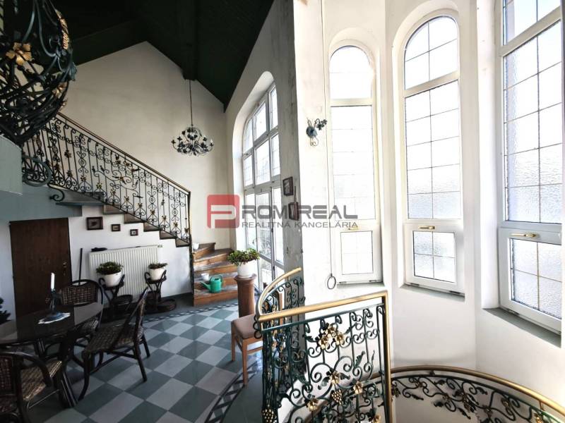 Innenraum eines Gebäudes mit dekorativer Treppe in der Ľ. Podjavorinská-Straße, große Fenster lassen Licht herein.
