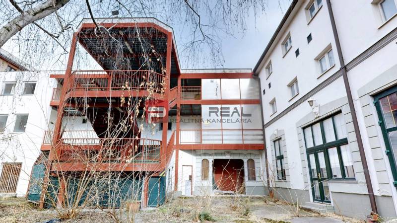 Das Gebäude in der Ľ. Podjavorinská-Straße in Trnava mit einer Außentreppe aus Metall und verglasten Fenstern.