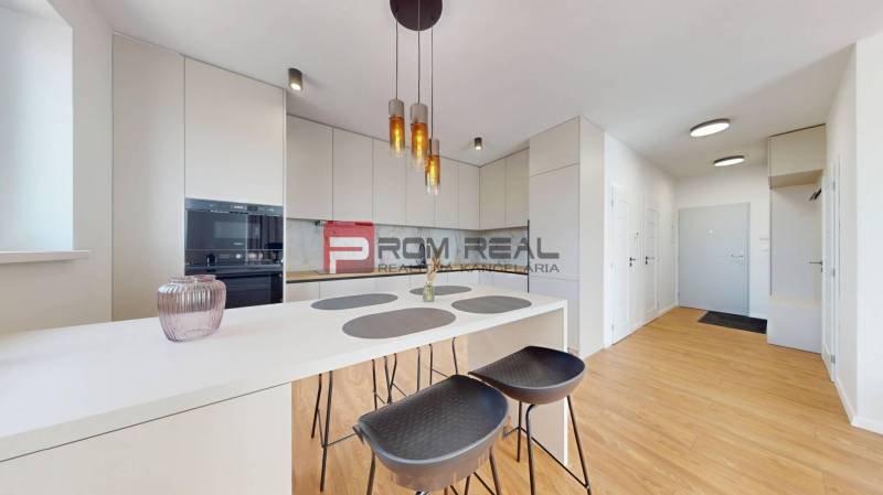 Küche in einer 2-Zimmer-Wohnung mit weißer Theke und Stühlen.