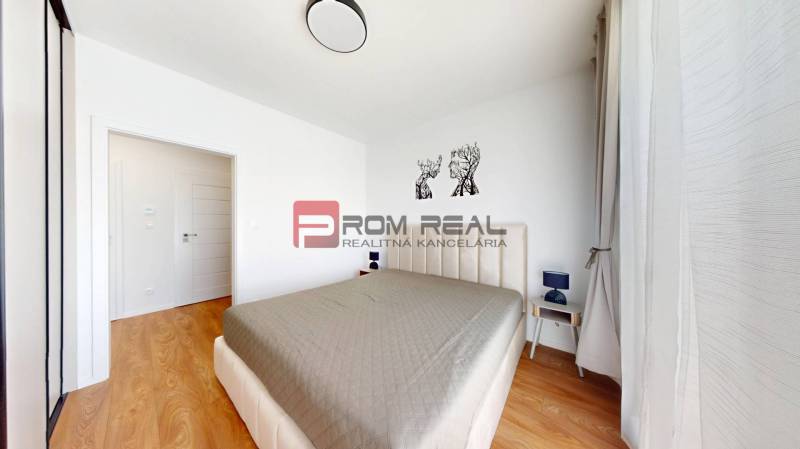 Schlafzimmer in einer 2-Zimmer-Wohnung mit einem großen Bett, Nachttischen und Bildern an der Wand.