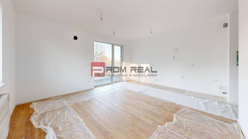 Helles Zimmer mit großen Fenstern und Holzboden in einer 2-Zimmer-Wohnung.