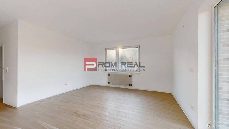 Ein Zimmer in einer 2-Zimmer-Wohnung mit weißen Wänden und Holzboden.
