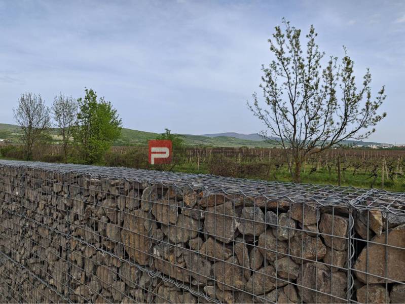 Gabionmauer in Pezinok mit Weinbergen und Hügeln im Hintergrund.