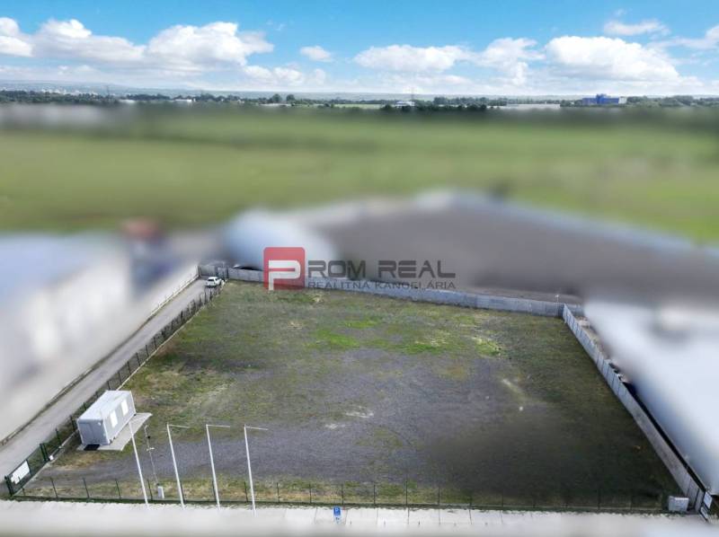Produktionsräume in Pezinok mit leerem eingezäuntem Grundstück und Containerobjekt.
