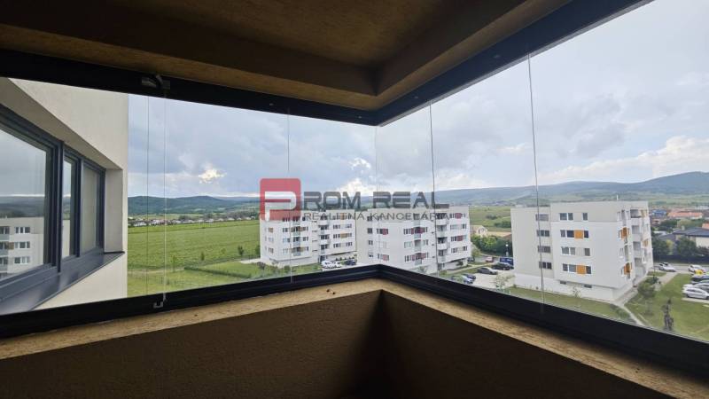 Blick vom Balkon einer 4-Zimmer-Wohnung auf grüne Felder und umliegende Gebäude in Pezinok.