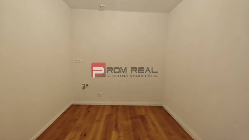 Ein Zimmer mit weißen Wänden und Holzboden in einer 4-Zimmer-Wohnung.