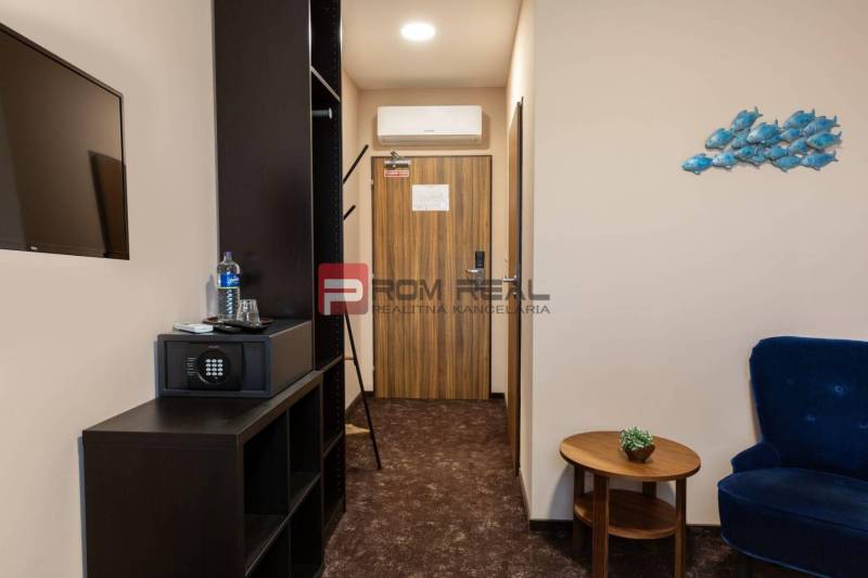 Ein Hotelzimmer mit Möbeln, einem Safe und einem Fernseher, Dekorationen an der Wand.