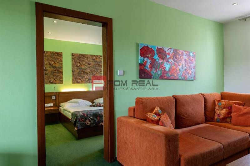 Das Innere der Pension mit einem orangefarbenen Sofa, Bildern und einem Bett mit bunten Decken.