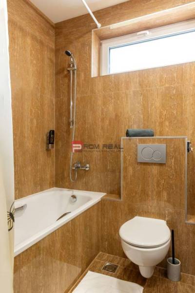 Badezimmer mit Badewanne und Toilette in Hotels und Pensionen, gefliest mit braunen Fliesen.