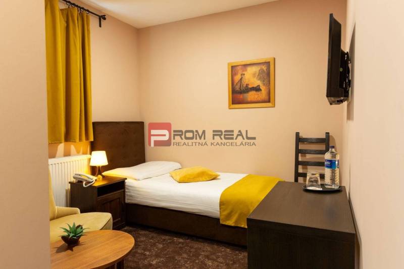 Gemütliches Zimmer mit Bett, Sessel und Fernseher, ideal für Hotels und Pensionen.