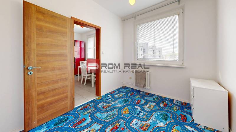 Kinderzimmer in einer 4-Zimmer-Wohnung mit blauem Teppich und Blick aus dem Fenster.
