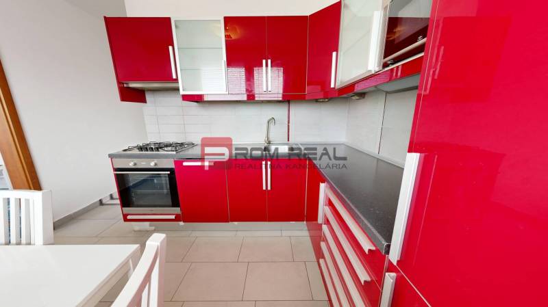 Rote Küche in einer 4-Zimmer-Wohnung mit Gasherd und weißem Tisch.