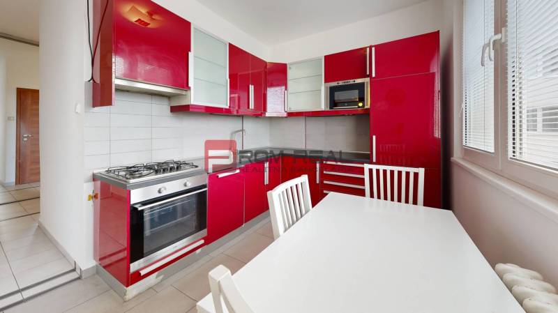 Küche mit roten Schränken und Gasherd in einer Vierzimmerwohnung.