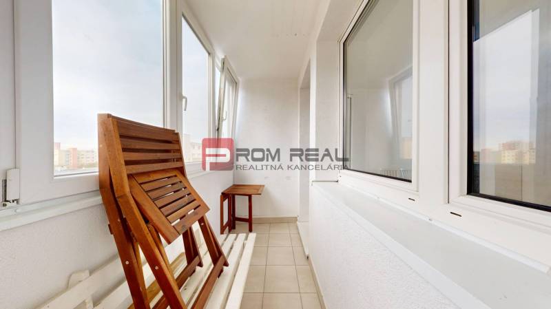 Verglaster Balkon einer 4-Zimmer-Wohnung mit Holzmöbeln und Blick auf die Stadt.