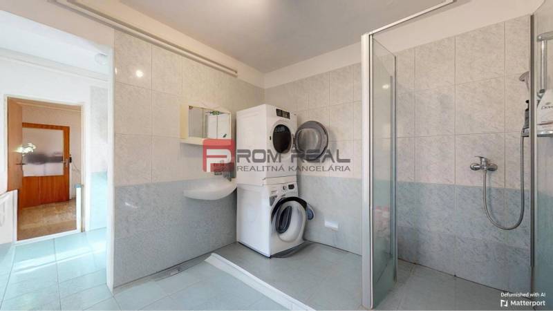 Badezimmer in einem Einfamilienhaus mit Waschmaschine, Trockner und Duschkabine.