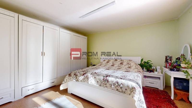 Schlafzimmer mit großem Schrank, Bett mit Blumenüberwurf in einem Einfamilienhaus.