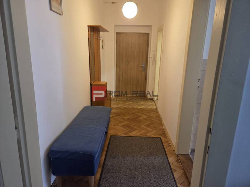 Der Flur mit einer blauen Bank und Holztüren, der eine 2-Zimmer-Wohnung einrichtet.