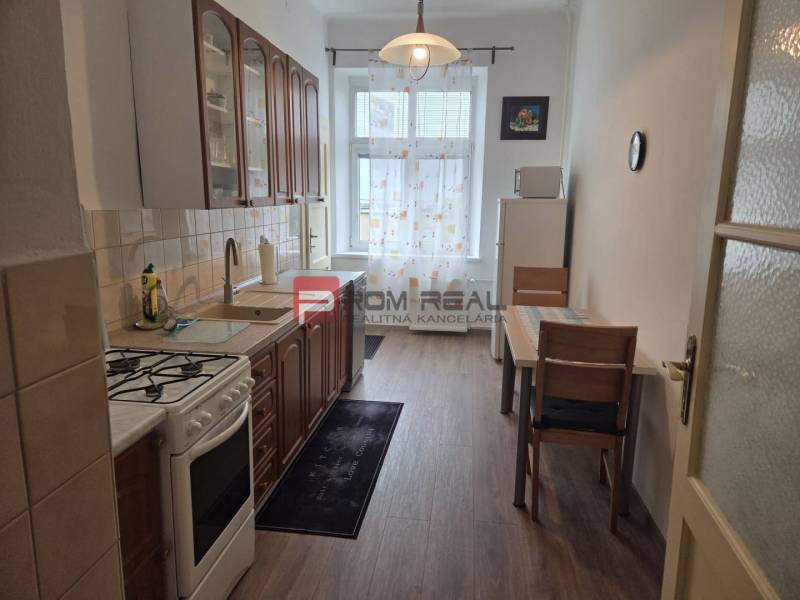 Küche in einer 2-Zimmer-Wohnung mit Gasherd, Esstisch und Schränken.