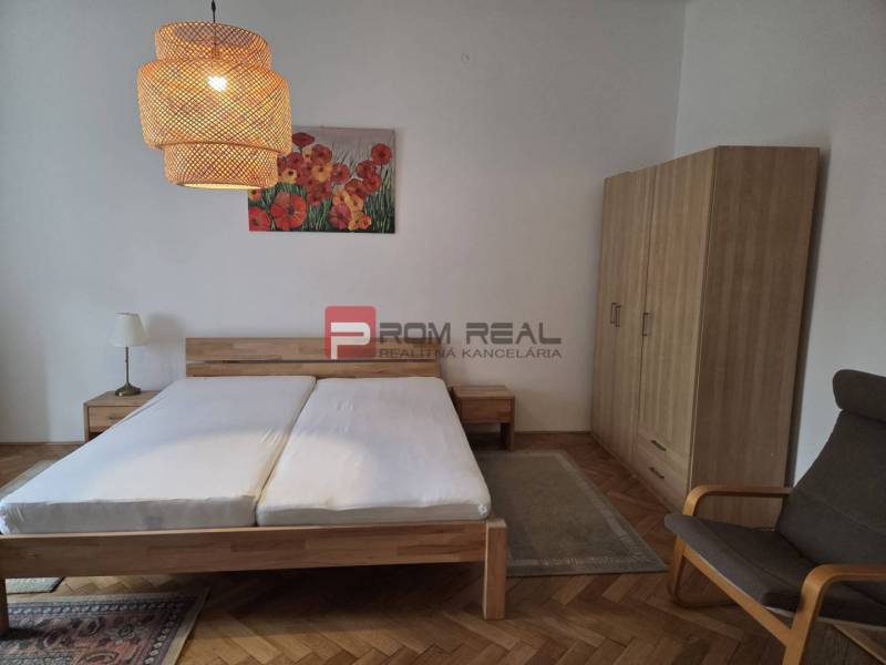 Schlafzimmer in einer 2-Zimmer-Wohnung mit Holzmöbeln, Kronleuchtern und einem Blumenbild.