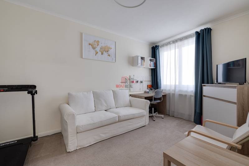 Zimmer in einer 3-Zimmer-Wohnung mit Sofa, Schreibtisch und Fernseher.