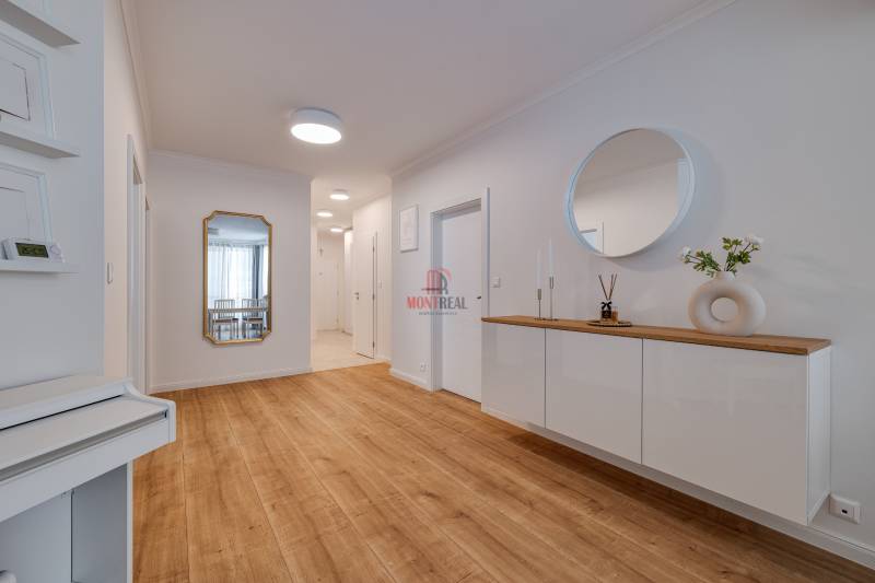 Eingangsbereich einer 3-Zimmer-Wohnung mit Holzboden, Spiegel und Schrank mit Dekorationen.