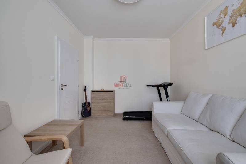 Ein Zimmer in einer 3-Zimmer-Wohnung mit einem weißen Sofa, einer Gitarre und einem Laufband.