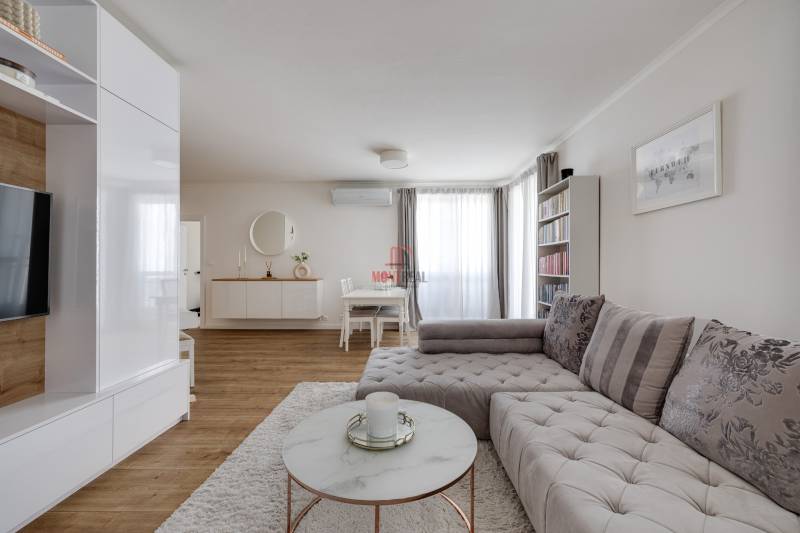 Wohnzimmer in einer 3-Zimmer-Wohnung mit stilvollem Sofa und minimalistischem Möbeln.