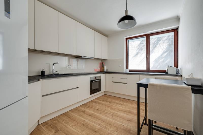 Küche in einer 3-Zimmer-Wohnung mit Holzboden und weißen Schränken.