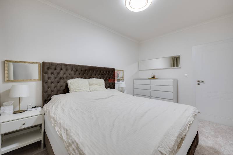 Schlafzimmer mit großem Bett, Nachttisch und Kommode in einer 3-Zimmer-Wohnung.