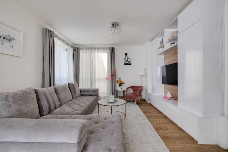Helles Wohnzimmer mit großem grauem Sofa und TV-Wand in einer 3-Zimmer-Wohnung.