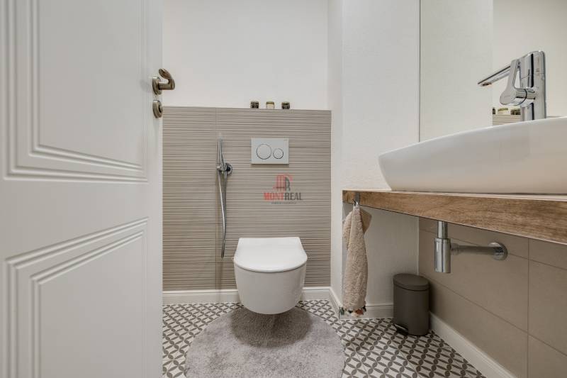 Badezimmer mit hängendem WC und Waschbecken in einer 3-Zimmer-Wohnung mit geometrischen Fliesen.