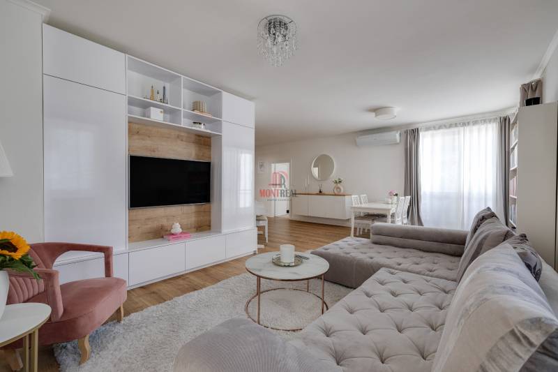 Wohnzimmer in einer 3-Zimmer-Wohnung mit bequemer Couch, TV-Wand und Esstisch.