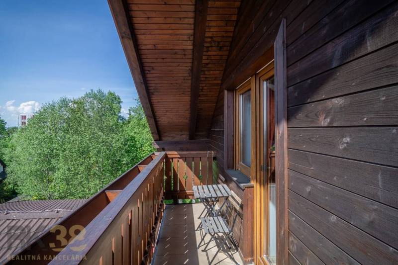 Balkon mit Tisch und Stühlen in einer Ferienwohnung mit Blick auf die Bäume in der Hohen Tatra.