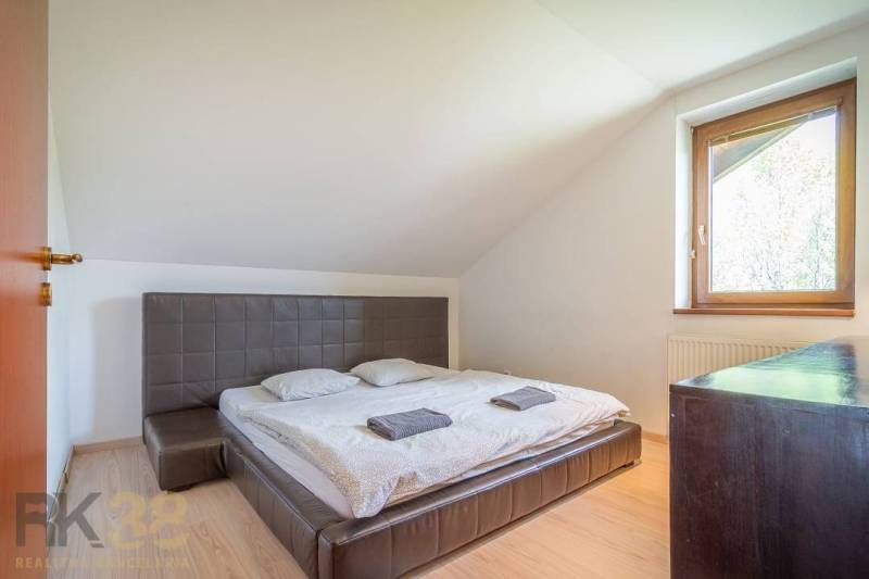 Schlafzimmer in einer Ferienwohnung mit Doppelbett, Fenster, Holzmöbeln und Dachschrägen.