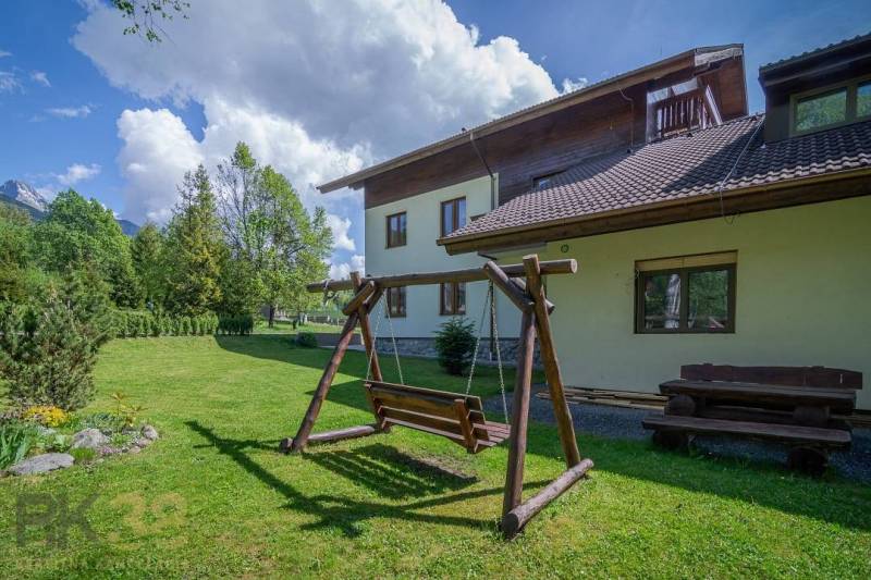 Garten mit einer Holzschaukel und einer Bank beim Ferienapartment in der Hohen Tatra.