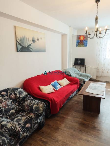 Wohnzimmer in einer 2-Zimmer-Wohnung mit einem Blumenmuster-Sessel, einem roten Sofa und einem Tisch.